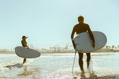 Sörf tahtası olan bir grup arkadaş dalgalar üzerinde sörf yapmak için okyanusa giriyorlar. Yüksek kalite fotoğraf 