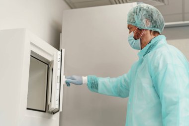 Tıbbi araştırma laboratuvarında çalışan üniformalı ve maskeli bir erkek bilim adamı. Yüksek kalite fotoğraf