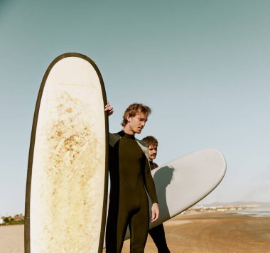 Dalgıç kıyafetli sörfçüler sörf tahtasıyla dalgalara binmeye hazırlanıyorlar. Yüksek kalite fotoğraf