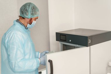 Tıbbi araştırma laboratuvarında çalışan üniformalı ve maskeli bir erkek bilim adamı. Yüksek kalite fotoğraf