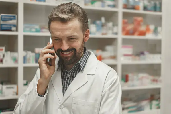 Male pharmacist using the computer and phone while working at the pharmacy
