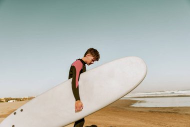 Dalgıç kıyafetli, sörf tahtası denize giren bir erkek sörfçü. Sörf ve okyanus. Yüksek kalite fotoğraf