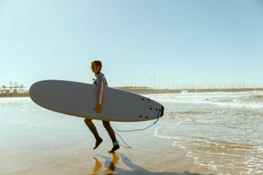 Dalgalar üzerinde sörf yaptıktan sonra sörf tahtasıyla denize giren dalgıç kılıklı mutlu bir kadın sörfçü.