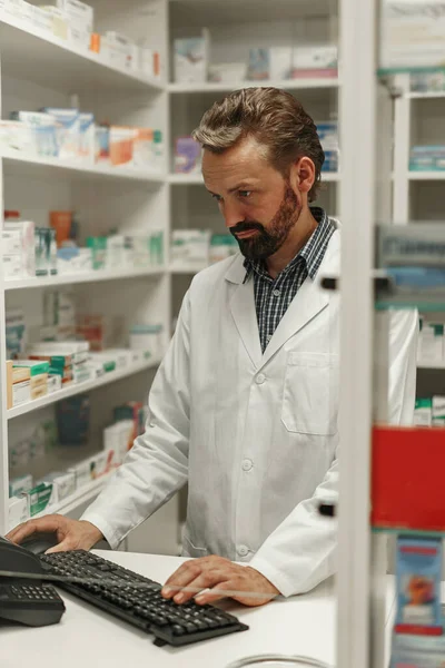 Male pharmacist using the computer while working at the pharmacy
