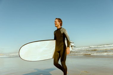 Dalgıç kıyafetli, sörf tahtası sörf yaptıktan sonra denize giren bir erkek sörfçü. Yüksek kalite fotoğraf