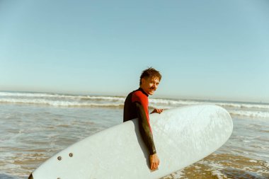 Dalgıç kıyafetli, sörf tahtası denize giren bir erkek sörfçü. Sörf ve okyanus. Yüksek kalite fotoğraf