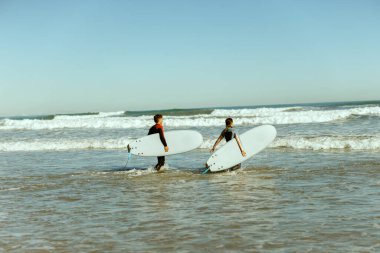 Sörf tahtası olan bir grup arkadaş dalgalar üzerinde sörf yapmak için okyanusa giriyorlar. Yüksek kalite fotoğraf 