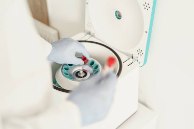 Bilimadamları eldiven takıp mikro santrifüje küçük bir plastik test tüpü yerleştiriyorlar.