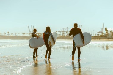 Dalgalar üzerinde sörf yaptıktan sonra sörf tahtasıyla denize giren sörfçüler.