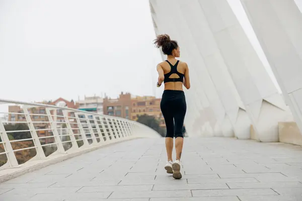 穿着运动服的年轻女子在现代建筑的背景下跑步 积极生活方式概念 — 图库照片