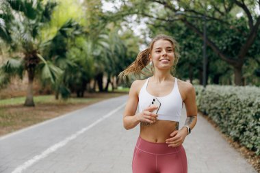 Aktif kadın sporcu sabah doğal park arka planında koşuyor. Sağlıklı yaşam konsepti
