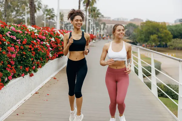 Twee Jonge Vrouwen Sportkleding Lopen Moderne Gebouwen Actieve Levensstijl — Stockfoto