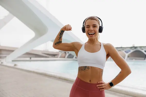 Mujer Sonriente Atleta Levantando Brazo Mostrando Bíceps Mientras Está Pie —  Fotos de Stock