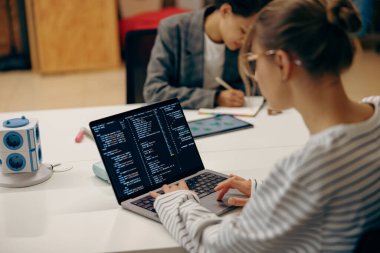 Genç bayan bilgisayar programcısı birlikte çalışırken dizüstü bilgisayarda kodlama yapıyor. 