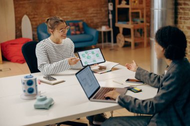 Mutlu iş arkadaşları birlikte çalışırken tablet bilgisayarın üzerinde tartışıyorlar.