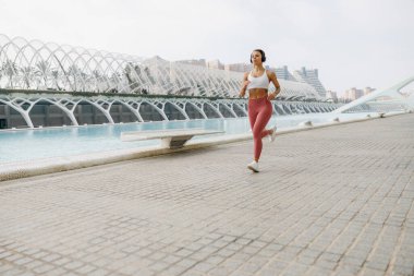 Spor giyim sektöründe genç bir kadın modern binalarda çalışıyor. Etkin yaşam tarzı kavramı