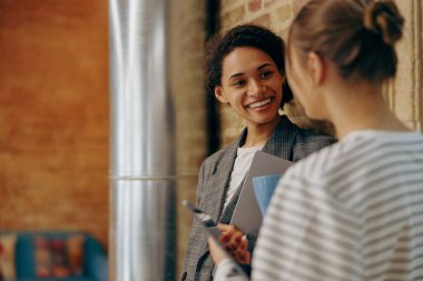 Gülümseyen kadın meslektaşlar konuşuyor. Kahkahalar atarak iş yerinde eğleniyorlar. Kurumsal kültür kavramı