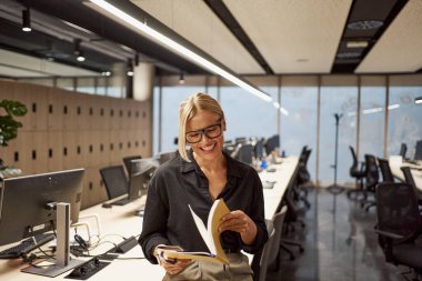 Şık ve şık bir profesyonel modern ofis ortamında büyüleyici bir kitaptan zevk alıyor.