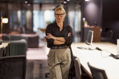 Kendine güvenen bir kadın şık ve modern bir ofiste profesyonelliğini ve çağdaş tasarım tarzını sergiliyor.