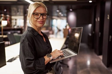 Kendine güvenen ve yetenekli bir profesyonel modern ve şık bir çalışma alanında çalışırken aktif olarak bilgisayarına bağlanır.