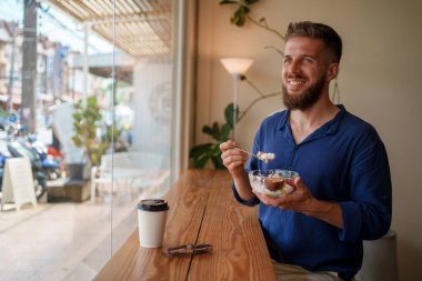 Mutlu bir adam, parlak bir kafede lezzetli bir tatlının tadını çıkarır.