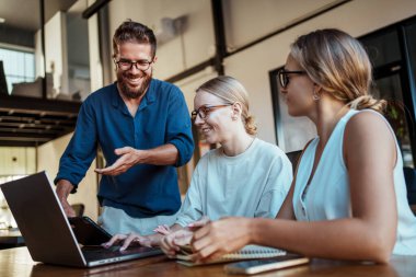 Dinamik bir ekip, şık ve çağdaş bir çalışma alanında dizüstü bilgisayar kullanırken zahmetsizce işbirliği yapıyor.