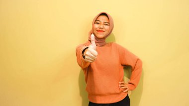 Genç Asyalı kadın farklı yönleri işaret ederek boş fotokopi alanını izole edilmiş turuncu arkaplanın üzerinde duruyor. İşaret parmağı. Yönlendirme