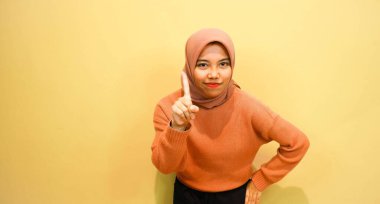 Genç Asyalı kadın farklı yönleri işaret ederek boş fotokopi alanını izole edilmiş turuncu arkaplanın üzerinde duruyor. İşaret parmağı. Yönlendirme