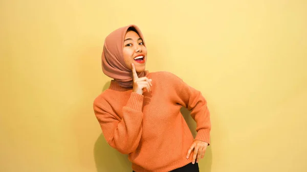 Emocionado Mujer Musulmana Asiática Vistiendo Suéter Naranja Hiyab Apuntando Espacio —  Fotos de Stock