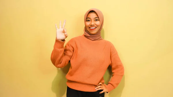 指を使って違う方向を指差してる若いアジアの女性孤立したオレンジの背景の上に空白コピースペースが立ってる 指を指してる 方向性を与える — ストック写真