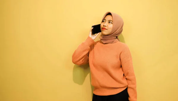 오렌지 스웨터를 아름다운 여성은 주황색 배경에서 스마트폰을 — 스톡 사진