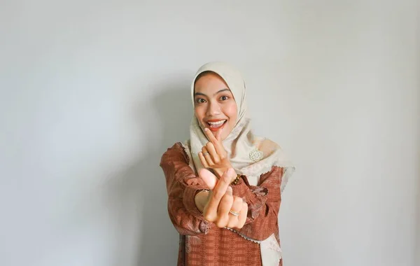2本の指で韓国の心を示す伝統的なイスラム教徒のドレスで美しい笑顔アジアの女性が交差し 白の背景に隔離された喜びと肯定を表現 — ストック写真