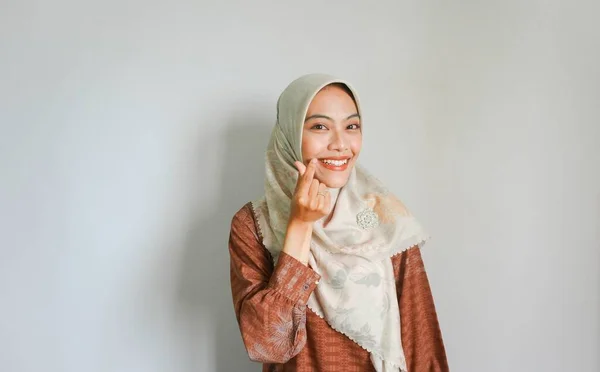 2本の指で韓国の心を示す伝統的なイスラム教徒のドレスで美しい笑顔アジアの女性が交差し 白の背景に隔離された喜びと肯定を表現 — ストック写真