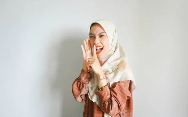 年轻美丽的亚洲穆斯林妇女头戴头巾大喊大叫 一只手捂着嘴 被白色背景隔开 传播概念 — 图库照片