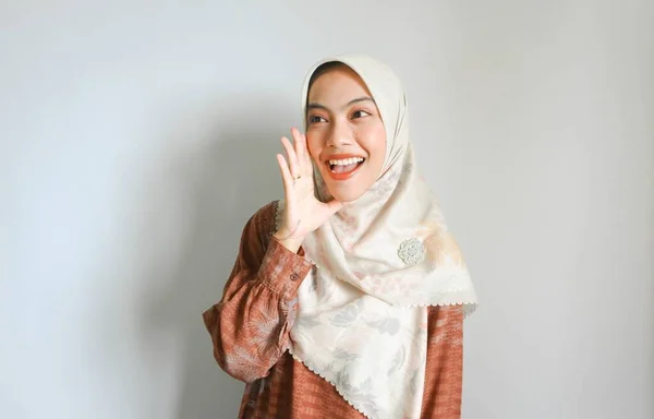白い背景に孤立した彼女の口の上に手で大声で叫んで叫んで大声でスカーフを身に着けている若い美しいアジアのイスラム教徒の女性 コミュニケーションの概念 — ストック写真