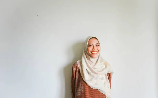 白い背景によって隔離された 彼女の横のコピースペースを指しているカジュアルなシャツとヒジャーブを身に着けている興奮したアジアのイスラム教徒の女性 — ストック写真