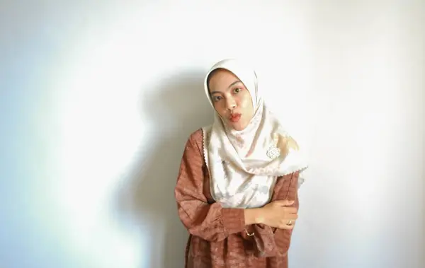 白い背景によって隔離された 彼女の横のコピースペースを指しているカジュアルなシャツとヒジャーブを身に着けている興奮したアジアのイスラム教徒の女性 — ストック写真
