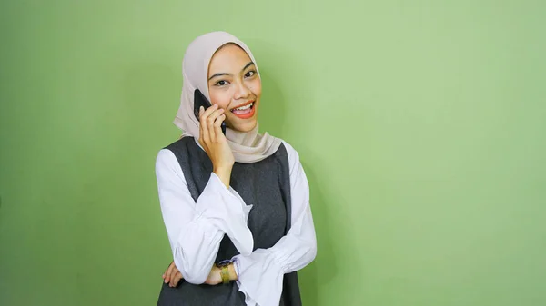 一个笑着的年轻亚洲女人用绿色背景的手机说话的画像 — 图库照片