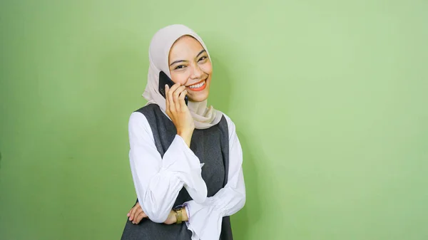 一个笑着的年轻亚洲女人用绿色背景的手机说话的画像 — 图库照片