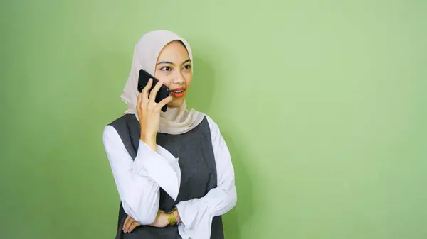 緑の背景に隔離された携帯電話で話している笑顔若いアジアの女性の肖像画 — ストック写真