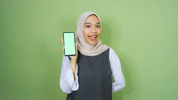 穿着头巾的年轻亚洲女人 在她的手机屏幕上显示复制空间 在绿色背景上被隔离 — 图库照片