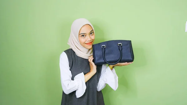 stock image Happy Asian girl woman holding black bag standing over green background studio shot, Close up Portrait of beautiful attractive young girl smiling looking at camera with bag