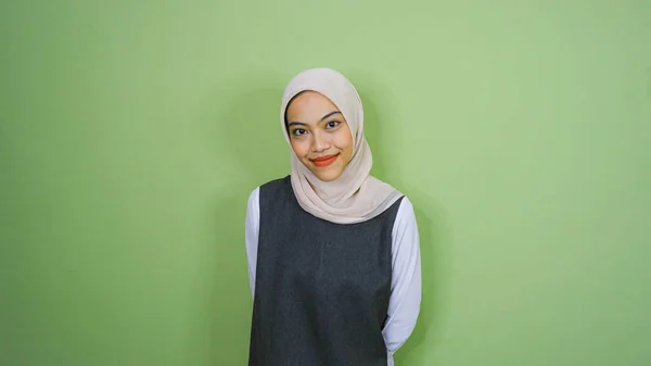 幸せなアジアのイスラム教徒の女性は カジュアルなシャツとヒジャーブを着て彼女の横にあるコピースペースを指して 緑の背景によって隔離された — ストック写真