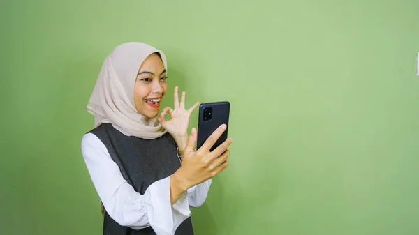 穿着休闲装的年轻亚洲女人开心地笑着 用绿色背景的智能手机打了一个视频电话 — 图库照片