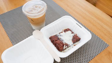 Kahve ve çikolatalı kek, tahta masada plastik bardakta..