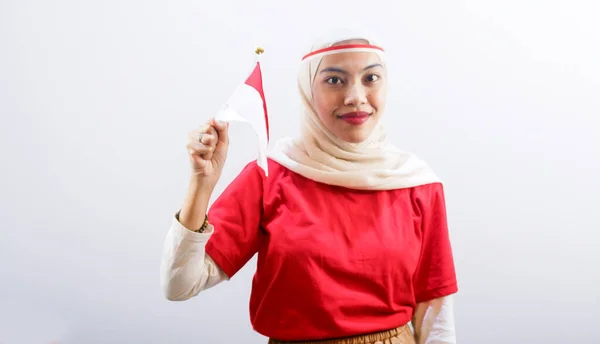 幸せな若いアジアの女性の肖像は 白い背景に隔離されたインドネシアの国旗を保持することによって 8月17日にインドネシアの独立記念日を祝います — ストック写真