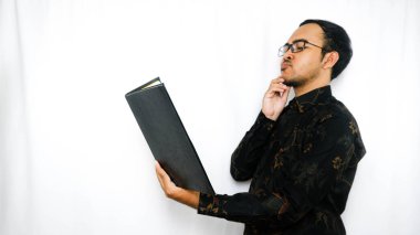 Batik giyen genç bir Asyalı 'nın portresi. Elinde beyaz arka plan üzerine bir kitap var.