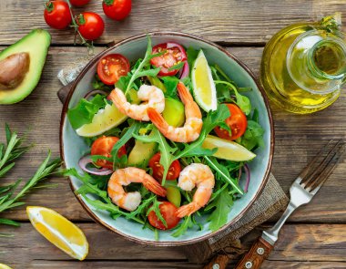 Fetuçin makarna karides, domates ve ahşap bir arka planda otlarla süslenmiş..