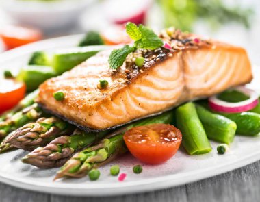 Kızarmış somon bifteğinin yanında kuşkonmaz, brokoli, havuç, domates, turp, yeşil fasulye ve bezelye. Taze sebzelerle karıştırılmış bir balık yemeği..
