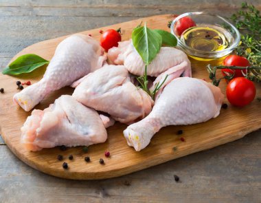 Çiğ tavuk kanatları (drumettes veya bagetler) ahşap bir tahta üzerinde sunulur.